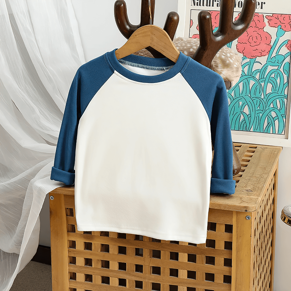Adorable kids' raglan sleeve top with a round neck in blue and cream hanging on a stylish wooden hanger.